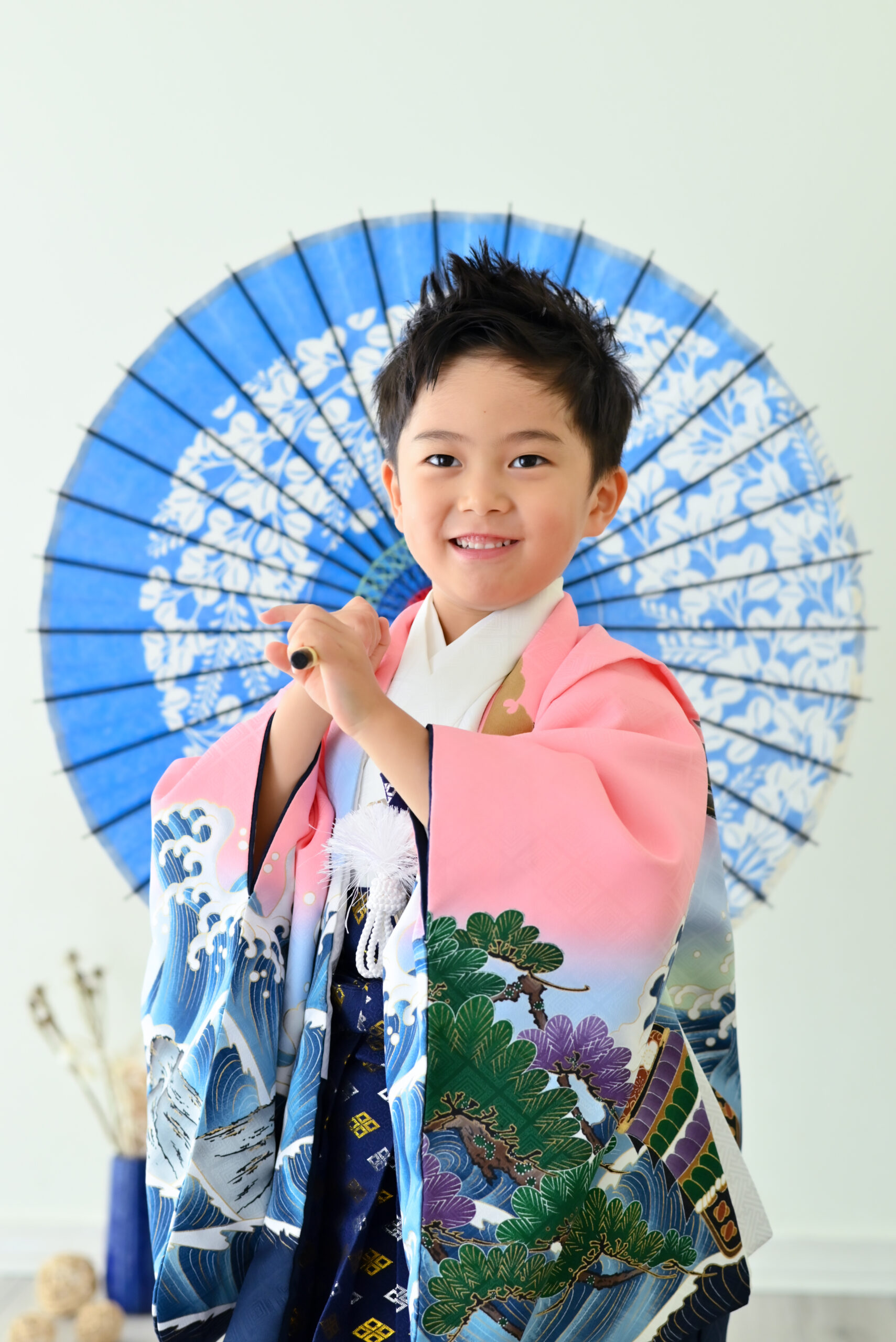 ピンクの袴を着た5歳男の子が青い傘を持っている