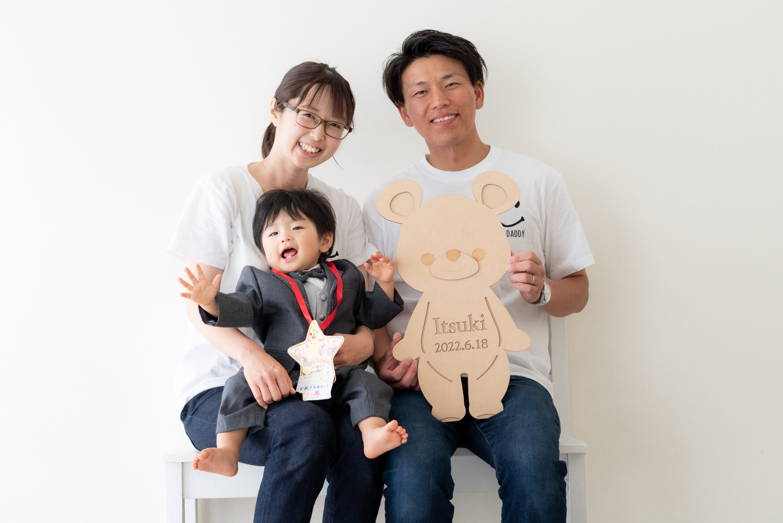 1歳の男の子とパパとママの家族写真 大きいクマさん形のお名前プレートを持っている